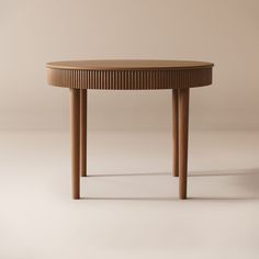 a wooden table with two legs and a circular top, on a white surface in front of a beige wall