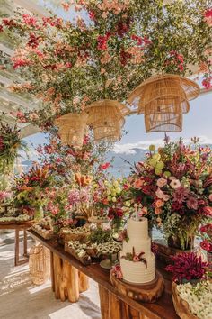 a table topped with lots of flowers next to baskets filled with plants and cake on top of it