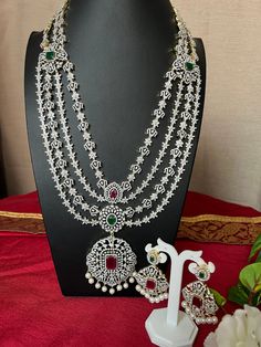 Grand Haram AD Diamond Ruby Emerald Doublet Stone/Bridal Haram/34 Inches Long Haram Ruby Stone/ Detachable pendant /South Indian jewelry This item is perfect for parties and festivals!  ITEM DETAILS: Handmade jewelry  Includes One Long Haram and Two Earrings. Necklace: 34.0 inches.total 34 inches long Wide 2.9 Pendent   Adjustable length. chain closure. Weighs 6.66oz (105 g).  Earrings:2.8 inch(es) long. Earring set weighs 0.75 oz (188g). Earring backs push on/off. Material: Imitation Micro gold, pearls Drop and. AD Stones. Finish: Premium Gold GJ Dimond Finish.  NOTE: I try my best to show you photos of my products as they appear in real life, but please note that variations in color occur due to differences in lighting and screen settings.  PRODUCT CARE: - Avoid contact with heat/fire, w Luxury Ruby Chandbalis In Temple Jewelry Style, Luxury Ruby Temple Necklace With Tilla, Wedding Necklace With Detachable Cubic Zirconia Pendant, Diamond Necklace With Detachable Pendant For Wedding, Silver Bridal Necklace With Detachable Pendant For Wedding, Detachable Pendant, Long Haram, Long Earring, South Indian Jewelry