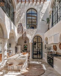 an indoor kitchen and dining area with white walls, arched doorways, and stone flooring