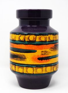 a purple vase with yellow and orange designs on it's sides, against a white background