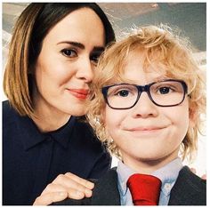 a woman standing next to a child wearing glasses and a suit with a red tie