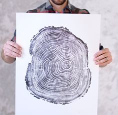 a man holding up a piece of paper with a tree ring drawn on it