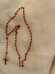 This is made using gold wire and red round beads. Every 10th stone is a red faceted bread. The cross is finished in 30 crystals surrounding a black shiny painted t shaped metal pendant. This can be used for any occasion Adjustable Red Cross Necklace, Red Adjustable Cross Necklace, Red Spiritual Jewelry With Gold Beads, Spiritual Red Jewelry With Gold Beads, Red Cross Pendant Necklace For Gift, Red Cross Pendant Necklace Gift, Red Spiritual Cross Pendant Jewelry, Red Crucifix Cross Necklace Gift, Red Crucifix Cross Necklace For Gift