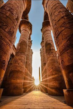 the sun shines through two large pillars in an ancient building with columns on each side