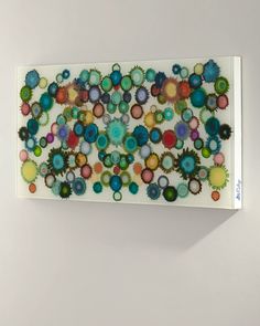 a white wall mounted art piece with colorful circles on it