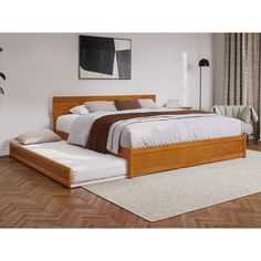 a bed sitting on top of a hard wood floor next to a white rug and window