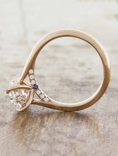 a diamond and gold ring sitting on top of a wooden table