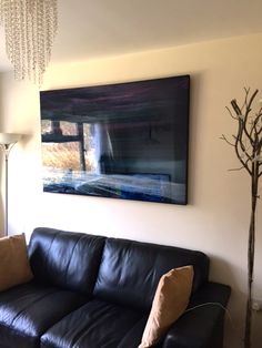 a living room with a black leather couch and chandelier hanging on the wall