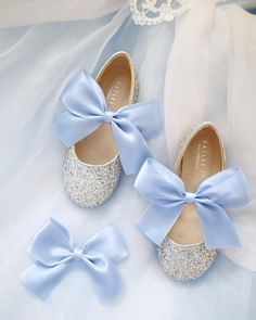 two pairs of baby blue shoes with bows on them, sitting next to each other