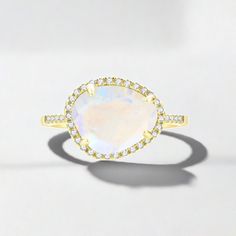 The Skye Moonstone Ring features a genuine Rainbow Moonstone surrounded by a halo of crystals on a pave band. Available in 14k Gold Vermeil or Sterling Silver. Rainbow Moonstone is a naturally occurring gemstone. Each one is beautiful and unique in its own way. These stones all many have variations in clarity, clouds and striations. Elegant White Topaz Rings With Gemstone Accents, Elegant Moonstone Ring With Gemstone Accents, Moonstone Diamond Ring With Halo Setting, Elegant Moonstone Ring With Gemstone Accents For Formal Events, Elegant Moonstone Rings In Diamond White, Elegant Moonstone Ring With Gemstone Accents For Formal Occasions, Elegant Gold Moonstone Ring With Diamond Accents, Elegant Formal Moonstone Ring With Gemstone Accents, Elegant Yellow Gold Moonstone Ring With Diamond Accents