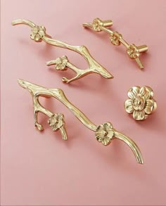 four pieces of gold metal on a pink surface