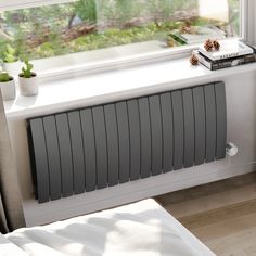 a radiator in front of a window next to a book and potted plant