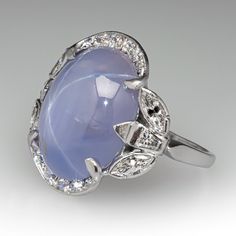 This stunning vintage ring is centered with an oval cabochon cut natural star sapphire set into a six-prong setting. The sapphire is bordered with ten (10), bead set, round brilliant cut diamonds, four (4), semi-bezel set, marquise brilliant cut diamonds and two (2), bezel set, tapered baguette cut diamonds. The ring measures 19.6mm at the top, rises 6.5mm above the finger, tapering to 1.4mm wide and 0.9mm thick at the base of the shank. It is currently a size 6. Luxury Domed Sapphire Ring Fine Jewelry, Luxury Heirloom Sapphire Open Ring, Luxury Cabochon Sapphire Wedding Ring, Vintage Oval Cabochon Gemstones, Vintage Gemstone Cabochons For Anniversary, Vintage Sapphire Ring With Oval Cabochon, Vintage Round Cabochon Gemstones, Vintage Round Cabochons For Anniversary, Star-shaped Gemstone Rings For Formal Occasions