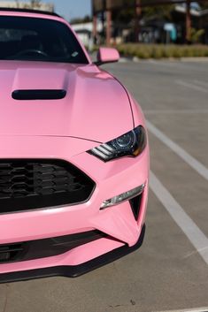 the front end of a pink mustang parked in a parking lot