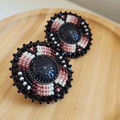 two black and pink beaded earrings sitting on top of a wooden table