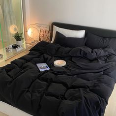 an unmade bed with black comforter and pillows on it in front of a mirror