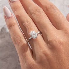 a woman's hand with a diamond ring on her finger and the other hand holding an engagement ring