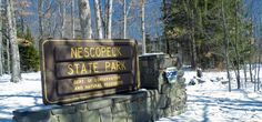 a sign that is in the snow near some trees