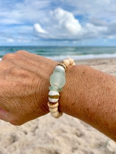 a person's arm with a bracelet on the beach