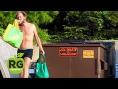 a shirtless man walking down the street with bags in his hand and a trash can behind him