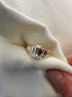 a woman's hand holding an engagement ring with three baguettes on it