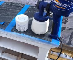 a blue and white paint sprayer sitting on top of a table next to a container