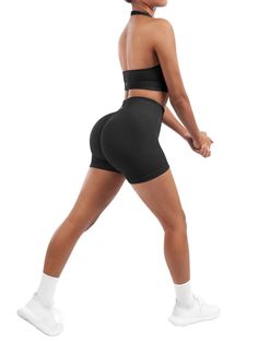 a woman in black shorts and sports bra top is walking with her back to the camera