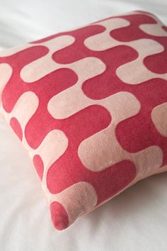 a red and white pillow sitting on top of a bed