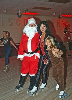 two women and a child are posing for a photo on roller skates with santa clause