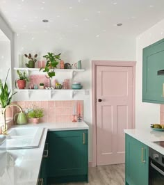 a kitchen with green cabinets and pink walls