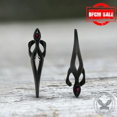 two pieces of black metal with red stones on the top and bottom, one is shaped like an antelope