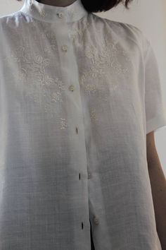 Vintage 60s hand embroidered blouse. Pure and fresh linen, a pleasure to wear. Mandarin collar, mother-of-pearl buttons, short sleeves and beautiful embroidery. Made in Italy. Excellent vintage conditions, a small defect (which you can see in the last photo), on the seam of one side near the bottom, not visible when worn. Best fit size S, M Shoulder to shoulder 41 cm Bust 52 cm (X2) Length 61 cm Model's size 8 UK h 163 cm Short Sleeve Tops With Chikankari Embroidery For Wedding, Elegant Short Sleeve Top With Chikankari Embroidery, Short Sleeve Linen Blouse With Floral Embroidery, Traditional White Blouse With Buttons, Classic Summer Blouse With Floral Embroidery, Classic Embroidered Short Sleeve Top, Classic Floral Embroidered Summer Blouse, Elegant Short Sleeve Blouse With Chikankari Embroidery, Vintage Linen Blouse With Buttons