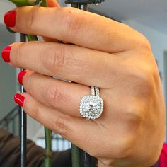 a woman's hand with a ring on it and a flower in the background