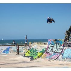 a man flying through the air while riding a skateboard in front of graffiti covered walls