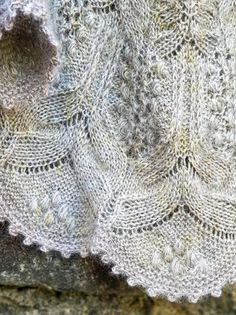 a close up of a knitted shawl on a rock