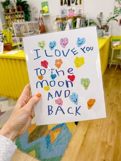 a person holding up a card that says i love you to the moon and back