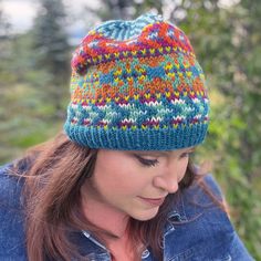 a woman wearing a blue jean jacket and a multicolored knitted beanie