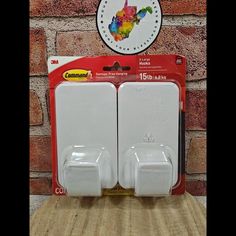 two white refrigerator magnets sitting on top of a wooden table next to a brick wall