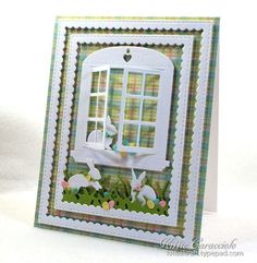 a card with an image of rabbits in the window and easter eggs on the grass