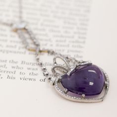 This antique amethyst and diamond drop necklace is truly something special - on the neck, it almost feels like an amulet that holds so much magic and life! Amethysts hold so much meaning, and are thought to bring cleansing, peaceful, and calming energy to the one wearing them. This heart-shaped cabochon has the dreamiest, deeply purple color to it, surrounded by a bow motif studded in rose cuts. Not to mention, the old mine cut and elongated oval diamond component that it hangs off of! This neck Formal Heart Cut Amethyst Jewelry, Luxury Purple Diamond Necklace, Luxury Amethyst Necklace With Diamond Accents, Luxury Purple Necklace For Anniversary, Luxury Purple Necklaces For Anniversary, Purple Diamond Necklace Fine Jewelry, Fine Jewelry Purple Diamond Necklace, Purple Diamond Necklace With Diamond Accents, Luxury Amethyst Jewel Necklaces