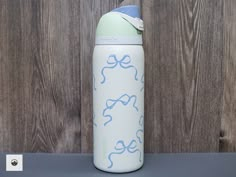 a blue and white water bottle sitting on top of a table next to a wooden wall