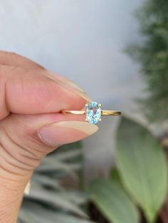 a woman's hand holding an engagement ring with a blue topazte stone