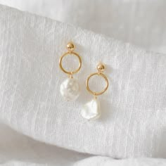 These earrings feature a simple gold circle finished with a dangling freshwater pearl. Made of 14K gold filled materials and genuine freshwater pearls, these earrings are tarnish-resistant, water-resistant, and hypoallergenic. Earring length measures approximately 1.5 inches long. --------------------♥ PROMOS ♥-------------------- Want 10% off? Join the mailing list by visiting http://bit.ly/vedern . Just leave me a note at checkout if you have any problems applying discount codes. ------------- Gold And White Earrings, Handmade Pearl White Minimalist Earrings, Handmade Minimalist Pearl White Earrings, Dangle Earrings As Wedding Gift, Dangle Earrings Jewelry Set For Wedding Gift, Minimalist Round Bridal Earrings As Gift, Pearl Earrings For Gift, Pierced, Handmade Dainty Earrings For Wedding, Dainty Handmade Earrings For Wedding