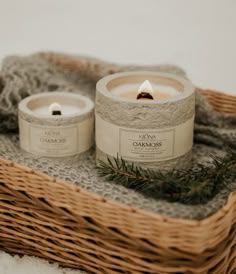 two candles sitting on top of a wicker basket