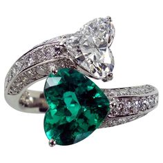 an emerald and diamond ring with two pear shaped diamonds