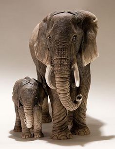 an adult and baby elephant standing next to each other in front of a white background