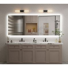 a bathroom vanity with two sinks and lights on the wall above it, along with a large mirror