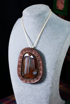 "Hand-sown and stamped leather pendant dyed brown, set with a lovely (huge red, white, and clear red agate carnelian cabochon. Window pane style! Both sides can be seen. 3.5\"x3\"" Brown Cabochon Pendant Jewelry, Artisan Brown Necklace With Oval Pendant, Artisan Brown Agate Necklace, Brown Cabochon Necklace For Gift, Artisan Brown Oval Jewelry, Brown Leather Necklace For Gifts, Brown Artisan Jewelry With Cabochon, Brown Carnelian Pendant Jewelry, Artisan Brown Jewelry With Cabochon