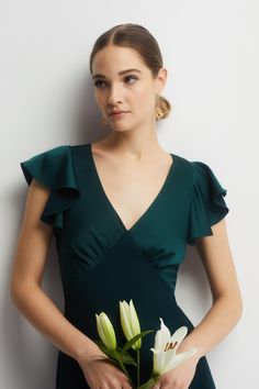 a woman in a green dress holding flowers